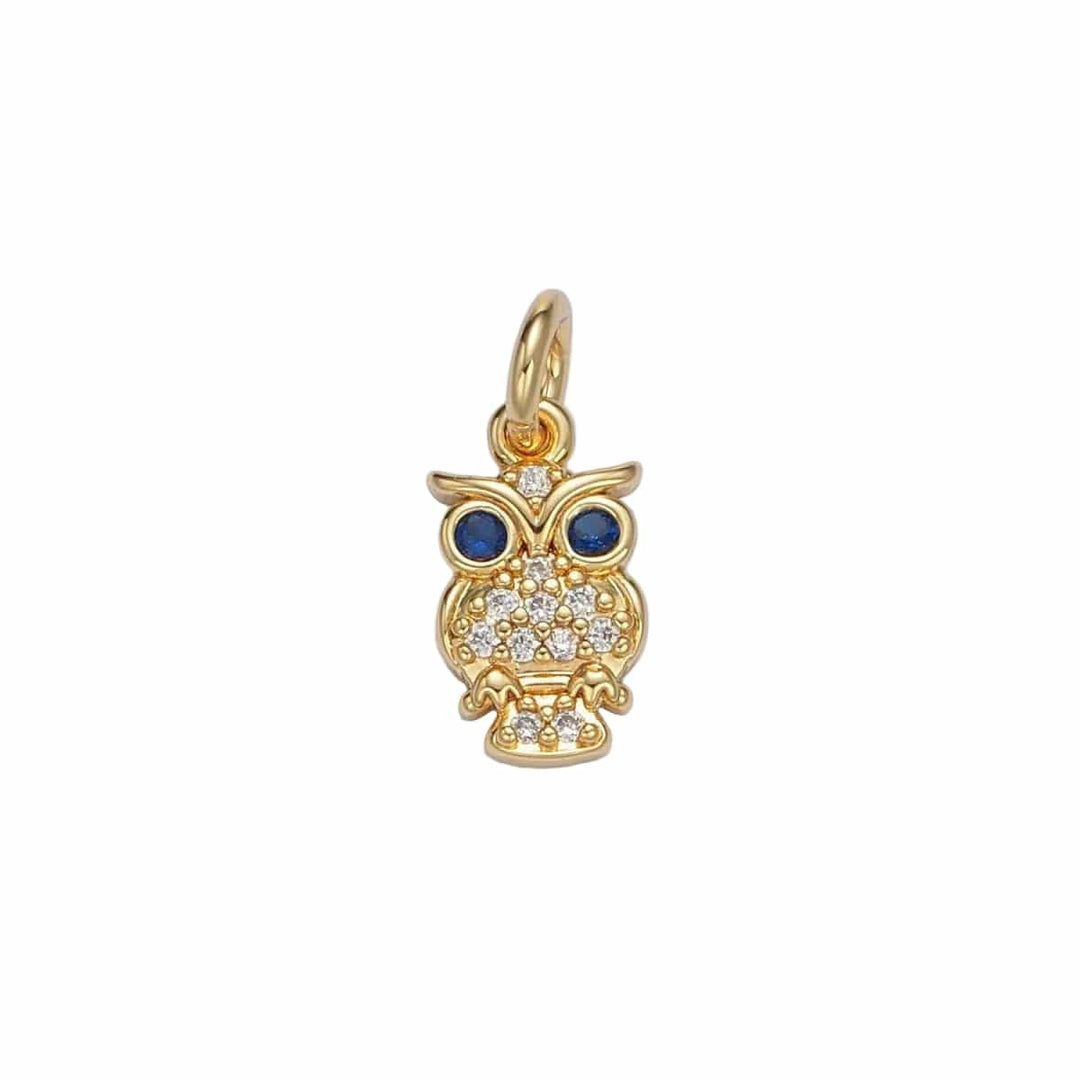 Gold owl pendant with blue eyes and clear stones on a light gray background