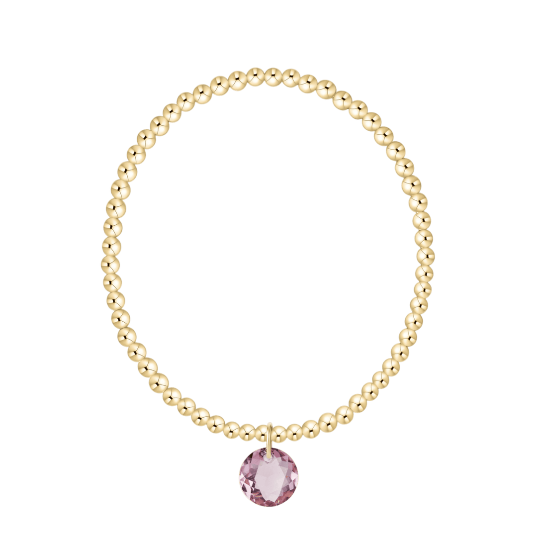 Gold bracelet with a pink gemstone on a white background