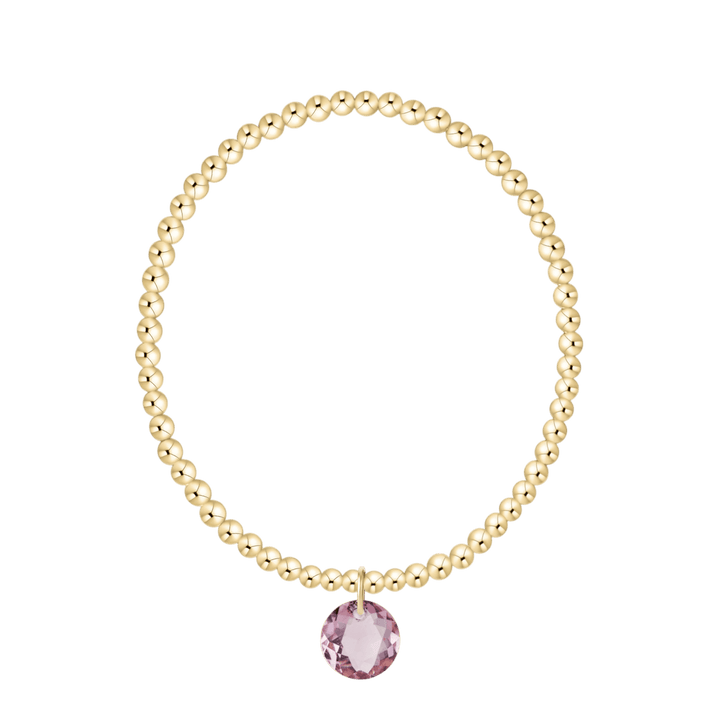 Gold bracelet with a pink gemstone on a white background