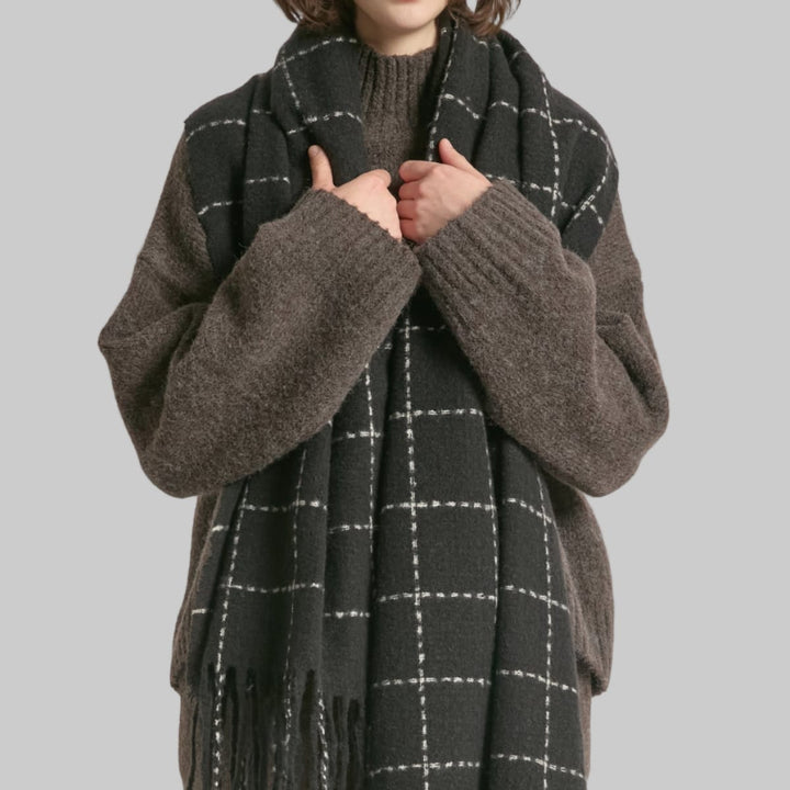 Person wearing a dark gray scarf with white checkered pattern on a plain background