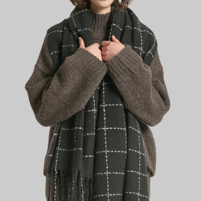 Person wearing a dark gray scarf with white checkered pattern on a plain background