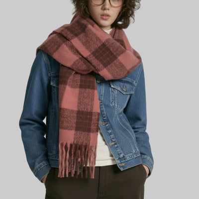 Person wearing a large plaid scarf and blue denim jacket on a plain background