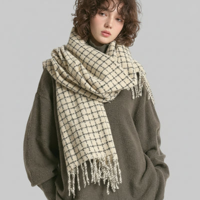 Person wearing a large checkered scarf and gray sweater on a white background